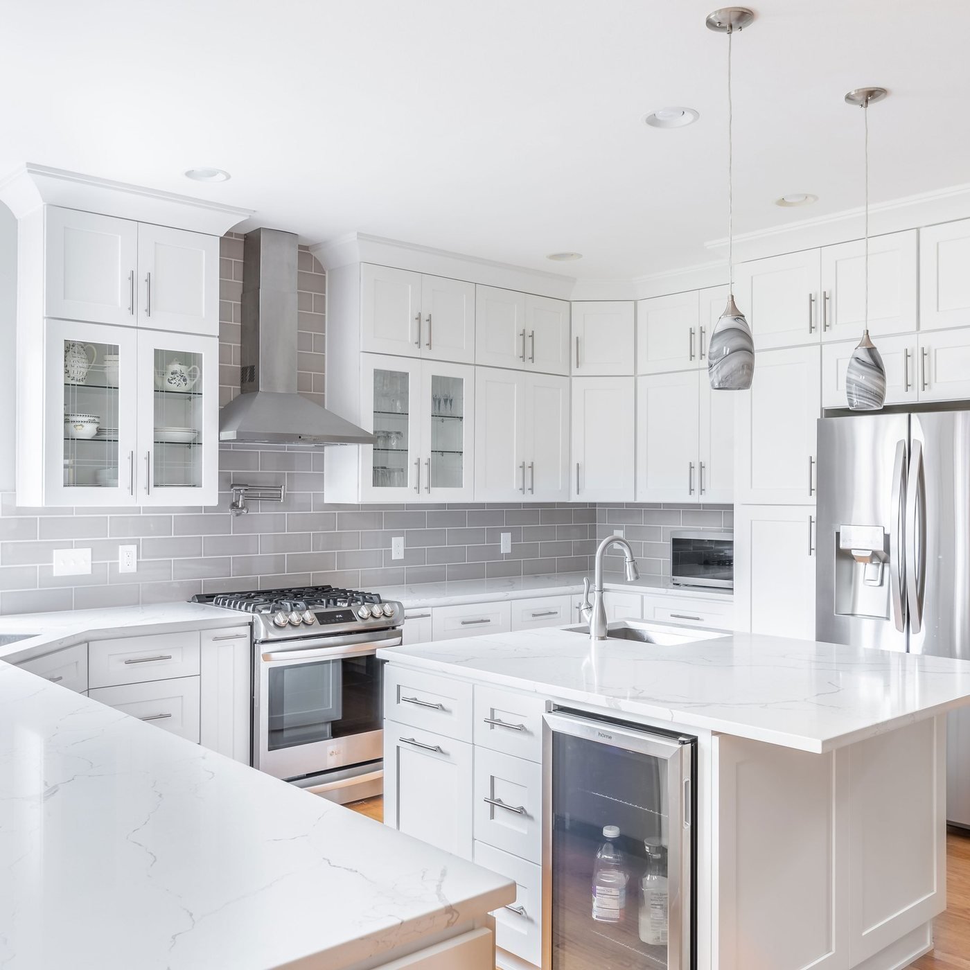 White kitchen with a corner sink and stainless appliances