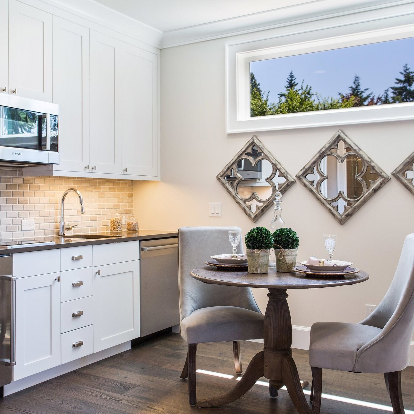 White kitchen with a breakfast nook and decorative mirrors