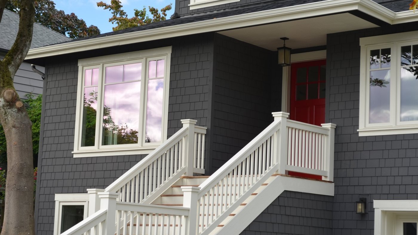 Home exterior remodel with new gray siding and a red front door