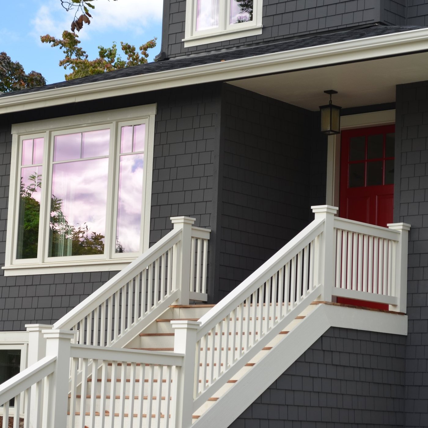 Remodeled home exterior with gray siding and a red door